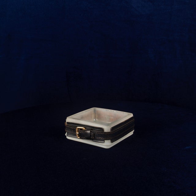 Overview An elegant leather ashtray by Jacques Adnet, France, 1950s. Hand-stitched saddle leather frames a metal ashtray...
