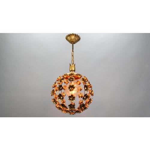 Hollywood Regency style gilt metal floral spheric pendant light, Italy, circa the 1970s. This beautiful gilt metal pendant...
