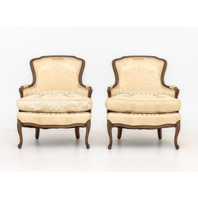 Pair of Louis XV Style Carved Wood Bergeres, white silk damask upholstery. 34" H x 29" W x 26" D; seat: 20" H. Provenance:...