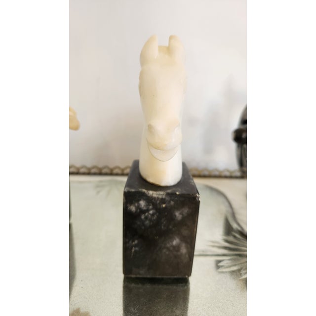 Vintage pair of carved stone horse head bookends with creamy white horse heads mounted on black stone cube bases. The...
