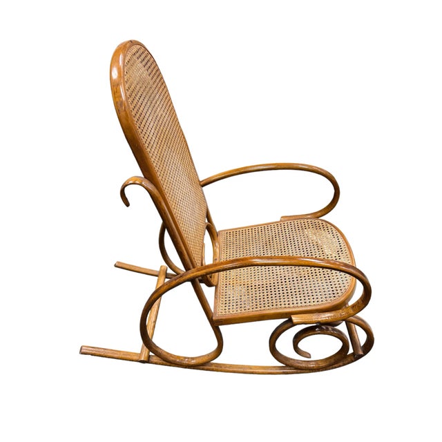 This rocking chair by Thonet is lightweight yet sturdy and compact enough for smaller spaces. Made from bentwood with cane...