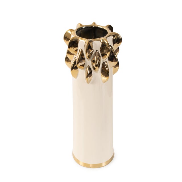 Finished in a smooth cream glaze and detailed with striking metallic gold accents, this vase brings a modern sense of...
