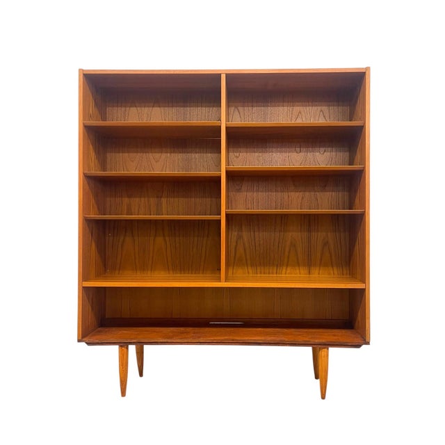 This vintage mid century modern bookcase features a clean-lined architectural form with a warm wood grain throughout. The...