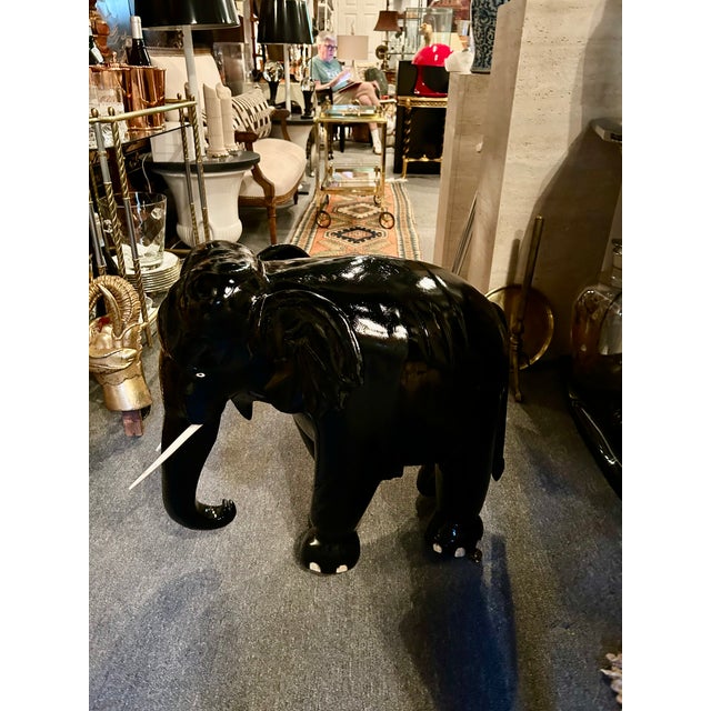 Striking and dramatic ebonized teak wood Elephant garden seat sculpture, having bone toenails and tusks. Brass casters...