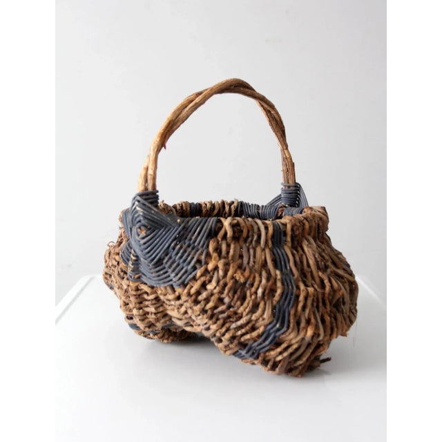 This vintage buttock basket features soft blue banding against its natural tone, with an arched handle and gracefully...