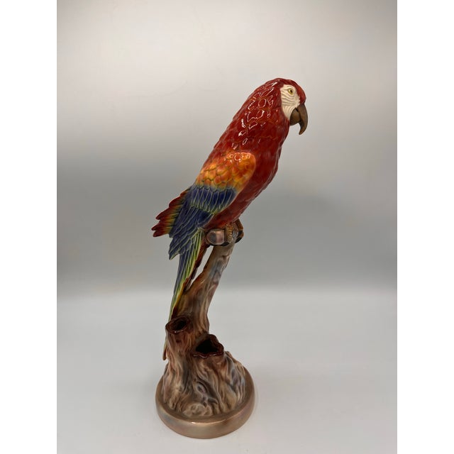 Large hand-painted parrot figurine with deep color palette and high gloss finish. Scarlet Macaw perched on tree stump....