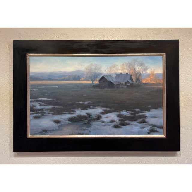 In "Remnants," a serene landscape unfolds, featuring a weathered farmhouse nestled among a tranquil expanse of melting...
