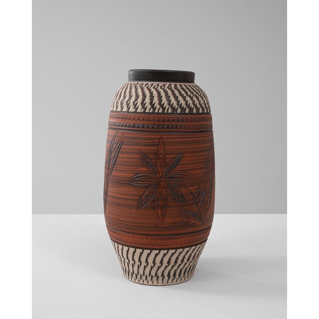 This 20th Century German ceramic jug features an intricate blend of carved floral motifs and geometric patterns,...