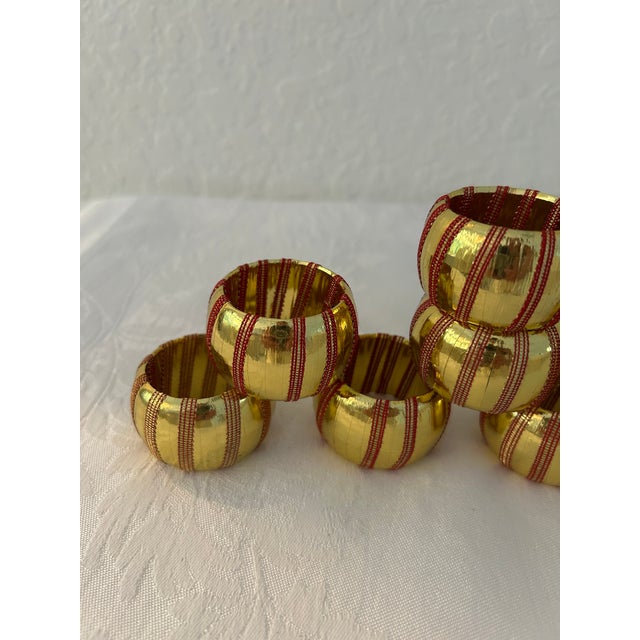 Festive set of eight vintage resin napkin rings wrapped in shiny gold foil with stripes of netted red and gold ribbon...