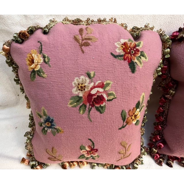 Pair of decorative pillows featuring a charming floral design on a soft pink background, finished with tassel trim....