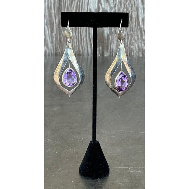 These vintage drop earrings are long, sculptural pendants that open with a polished teardrop-shaped cap and a fine wire...