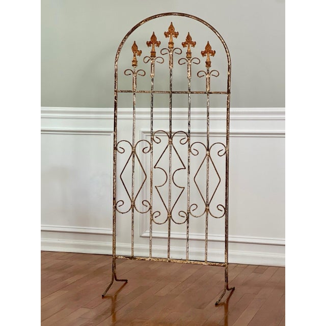 A free standing and perfectly weathered arch form wrought iron white painted trellis. A charming architectural element...