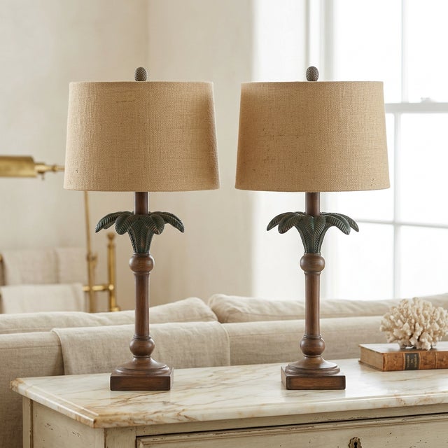 Trendsetting pair of Hollywood Regency style table lamps. They are made of metal with a palm tree motif. Each has arching...