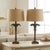 Trendsetting pair of Hollywood Regency style table lamps. They are made of metal with a palm tree motif. Each has arching...