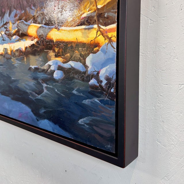 Reflection Point captures a serene winter scene where a figure balances on a fallen log, poised above a gently flowing...