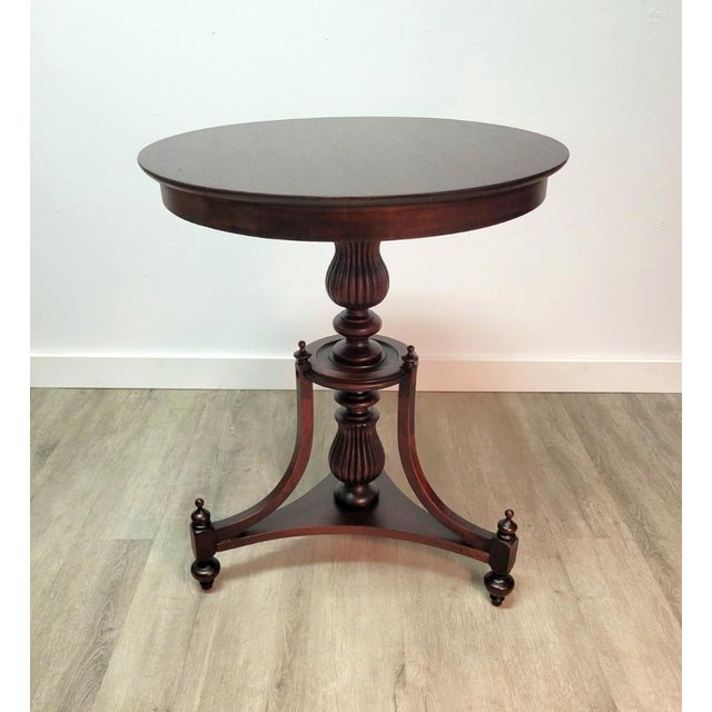 A refined mahogany pedestal table in the American Classical tradition, featuring a circular top raised on a beautifully...