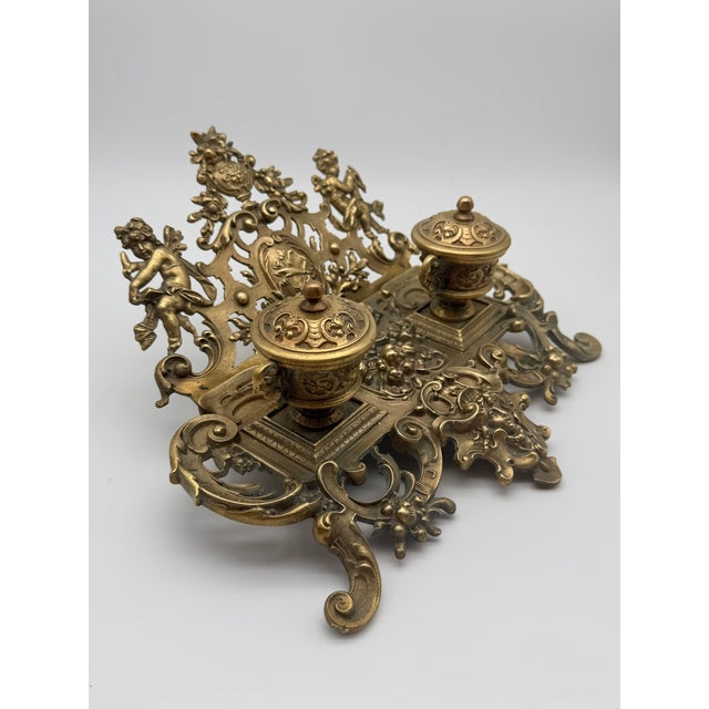 Elevate your desktop or library display with this remarkably ornate antique French Rococo cast brass double inkwell,...