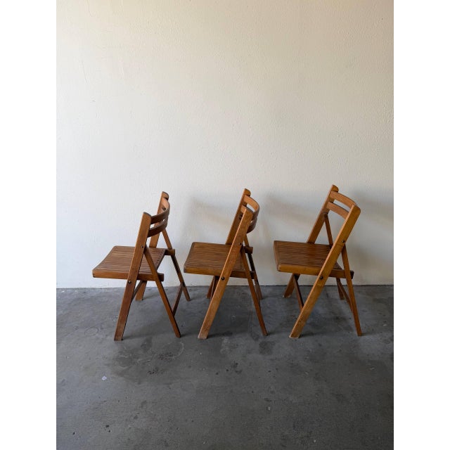 Set of three mid century modern folding chairs, circa 1970s. These vintage wooden folding chairs feature clean modern...