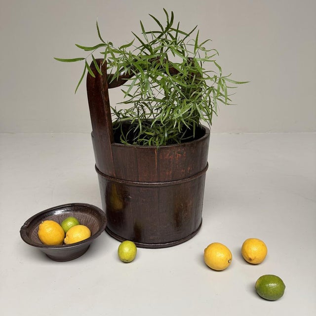 This traditional Japanese wooden bucket, or teoke, is a large and remarkably warm utilitarian object with a strong,...