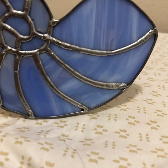 Beautiful handmade stained glass sun catcher featuring a blue ammonite design. When the light hits it, the glass glows...