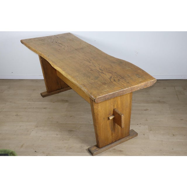 A remarkable piece from the 1950s/60s, this solid wood dining table stands out as a true sculptural work, where the...