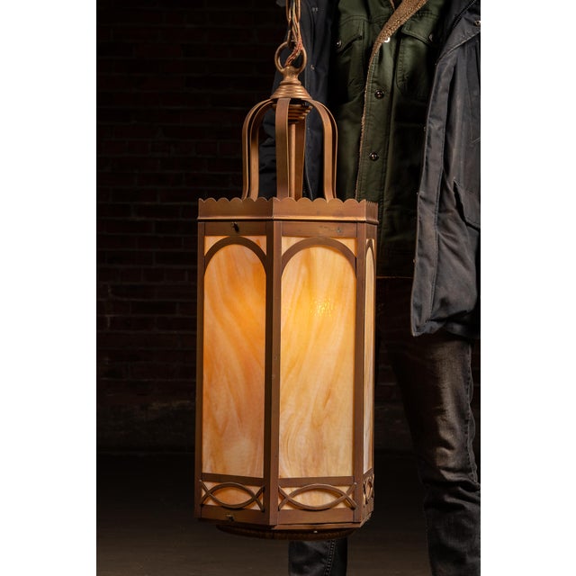 Mid-century lantern-form pendant featuring a tall hexagonal frame in a warm bronze-tone finish with translucent faux...