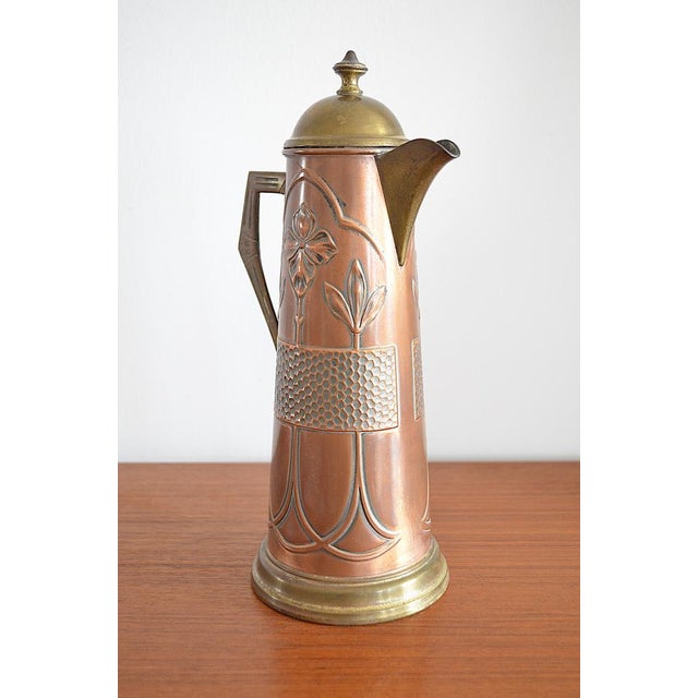 Art Nouveau copper pitcher with a typical floral lily motif. Similar pitchers were manufactured by WMF; unfortunately,...