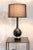 A handsome American Mid-Century table lamp dating to the 1960s, featuring a sculptural matte black ceramic body resting on...