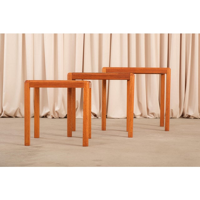 A set of three Danish modern nesting side tables in teak with ceramic tile inset tops, a practical and visually warm...