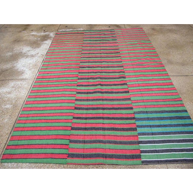This Mid-20th century Turkish Flatweave Kilim rug, presents a lively striped design that embodies the bold color...