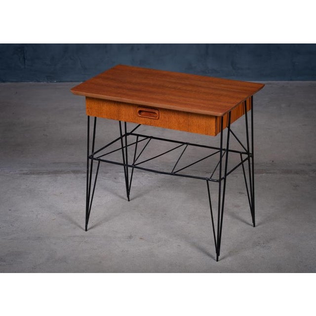 Elegant bedside or side table in teak with a sleek metal frame, combining warm wood tones with a light, modernist...