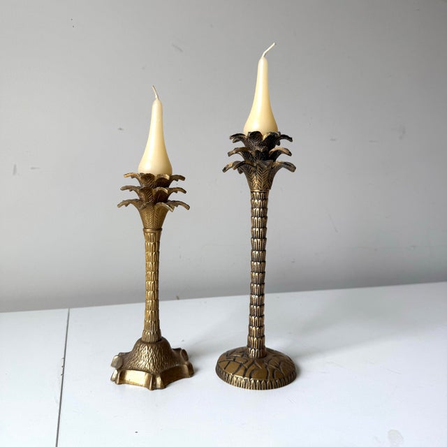 Vintage pair of brass palm tree candlestick holders. Each are varied in design and tiered in height.