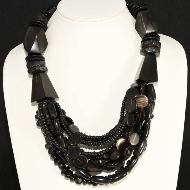 Necklace featuring multi strands of beads crafted of dyed horn and ebony wood. Some of the elements have a bit of a...