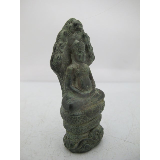 Antique Bayon style Khmer bronze figurine depicting the Buddha sheltered by the Naga serpent king Muchalinda. The Buddha...