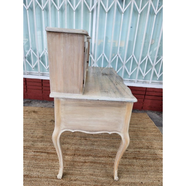 Ornate wooden secretary desk has a light-washed finish with visible wood grain. This piece features a hutch with two side...