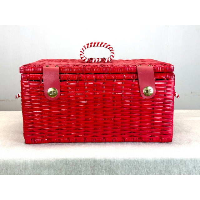 A fun and funky woven red plastic picnic basket with white and red striped handles and gold finish and faux leather clasps...