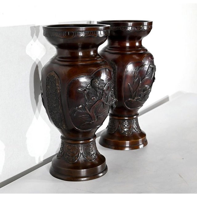 This pair of bronze vases with nuanced brown patina, dating from the 20th century. Each vase is with distinct decorations...
