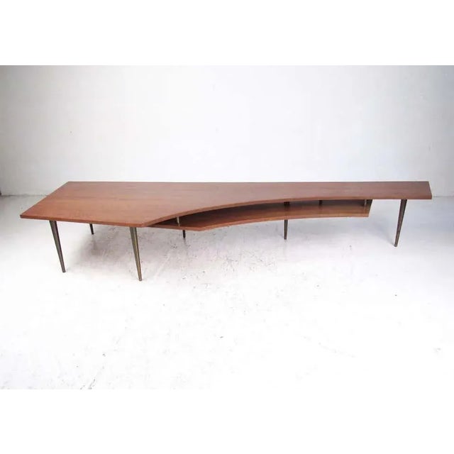 This large-scale two-tier coffee table features distinctive midcentury design, tapered bronze finish legs, and...