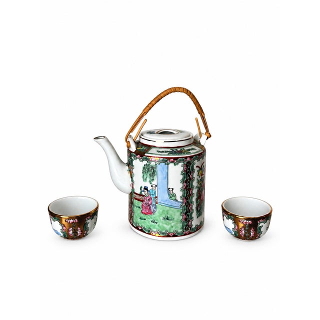 A richly decorated Chinese porcelain tea set featuring a cylindrical lidded teapot and two coordinated handleless cups....
