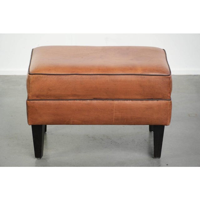 This handy sheepskin footstool features a warm color scheme and is finished with black piping. A footstool, also known as...