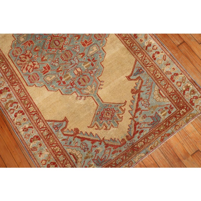 An early 20th century hand-woven decorative persian serab rug, khaki field with teal medallion and border, accent in brick...