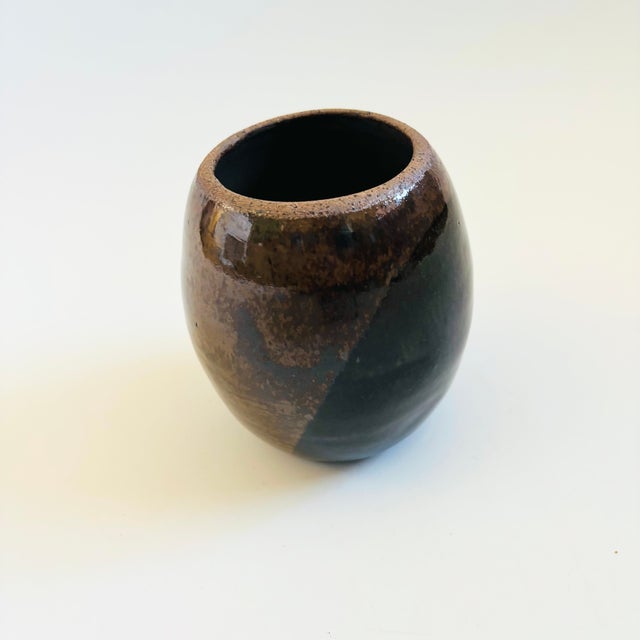 A handmade vintage studio pottery vase. Nice round shape and versatile size. Overlapping glaze pattern in dark brown and...