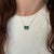 An emerald glows with green brilliance at the heart of this emerald cut pendant, framed by a trail of brilliant natural...