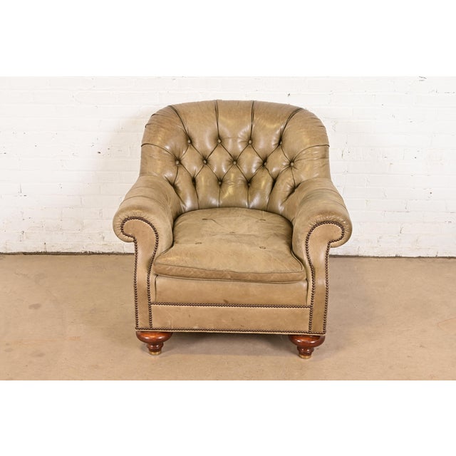 An outstanding late Victorian leather upholstered deep tufted club chair or tub chair with scrolled arms on turned bun...