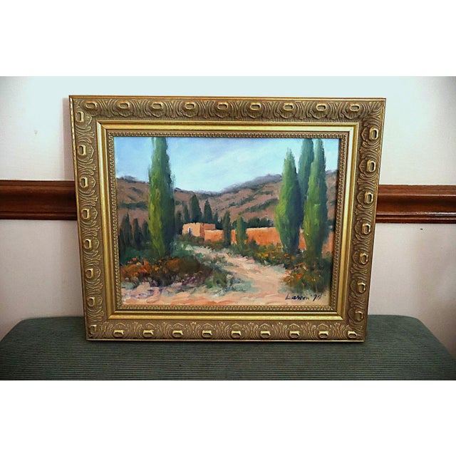 An original 1977 oil on canvas landscape signed Larson, depicting a sunlit Southwestern countryside with adobe-style...