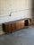 This minimalist lowboard features a long rectilinear frame elevated by tapered peg legs. The four sliding doors glide open...