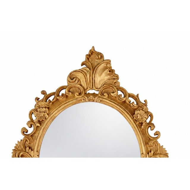 A vintage Rococo-style gold oval wall mirror with carved decorations. These mirrors typically feature delicate vines,...