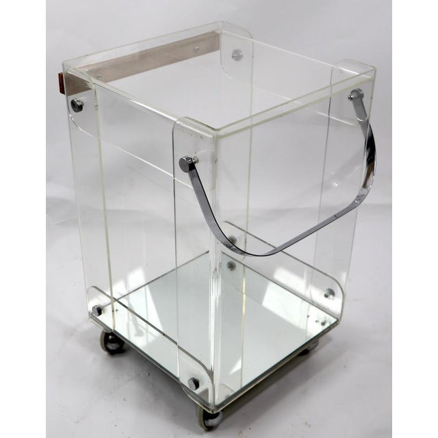 Chic serving cart in Lucite with chrome handle, mirrored bottom shelf, and wood butcher block top. This service trolley is...