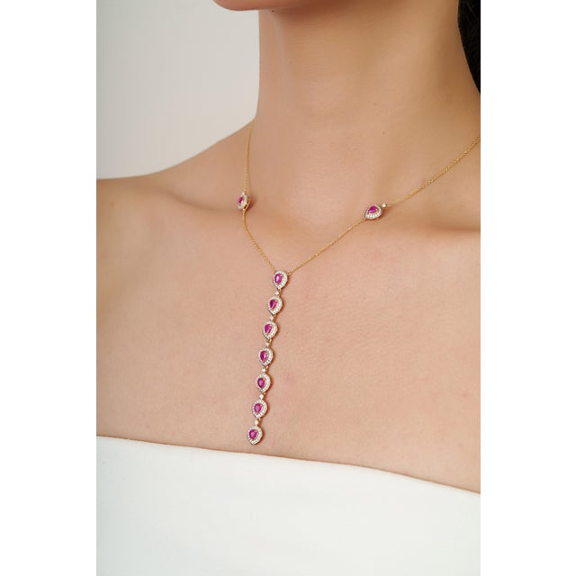 This lariat necklace features 2.16 carats of red rubies set in 14K yellow gold, measuring approximately 4 x 3.5 mm,...