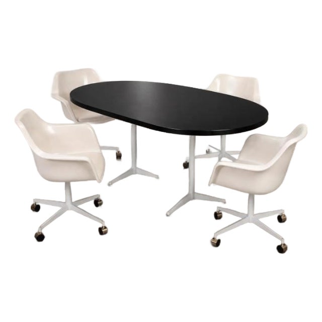 Striking vintage mid century modern dining or conference set featuring a black oval table paired with four matching white...